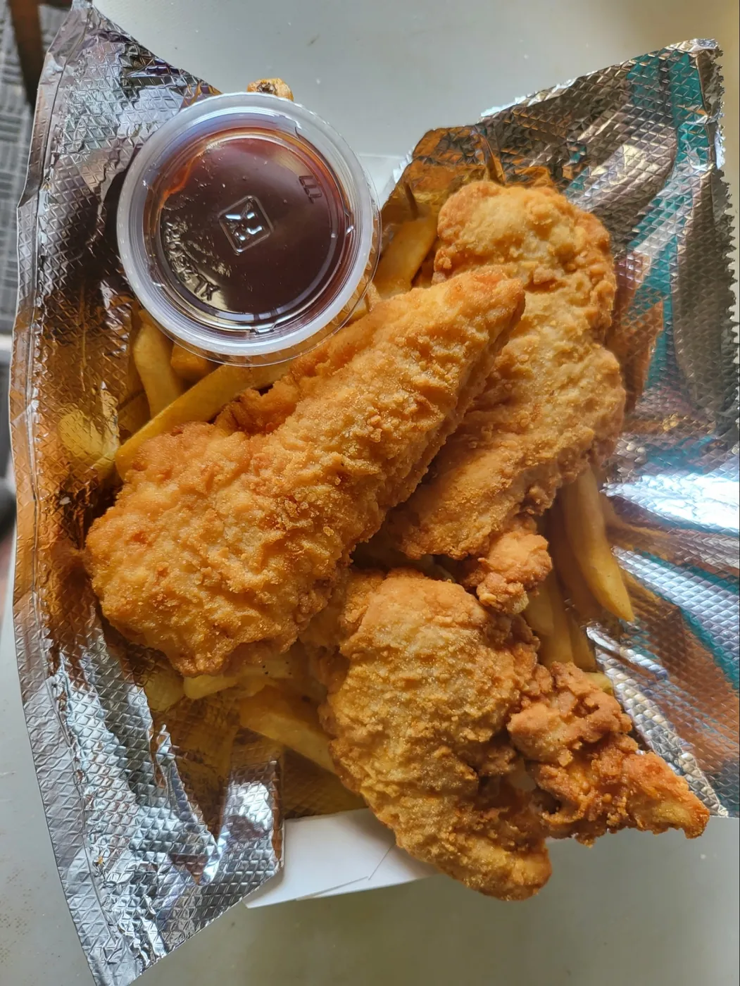 Hand-breaded chicken tenders and fries with dipping sauce.