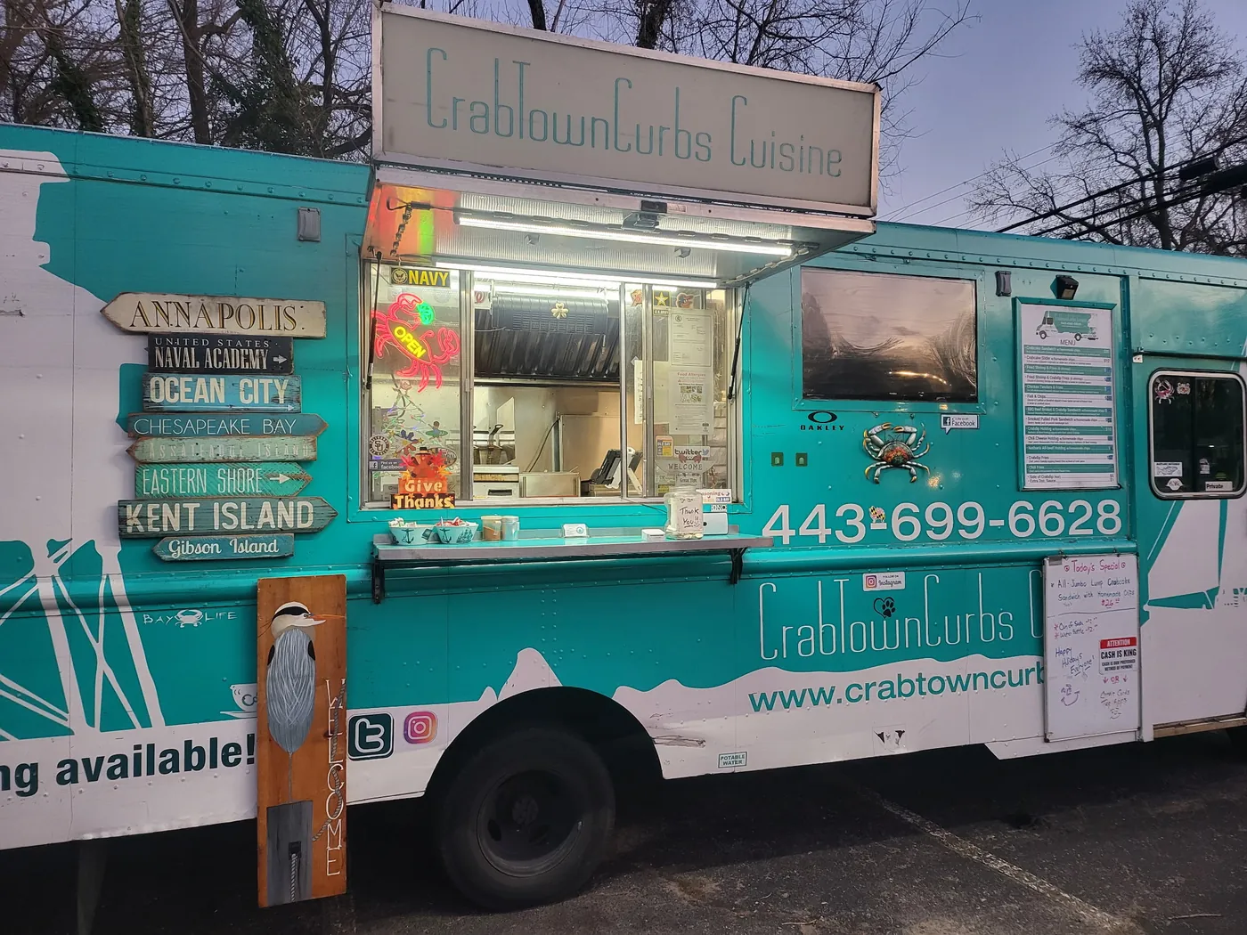 The teal CrabTown Curbs food truck lit up at dusk.