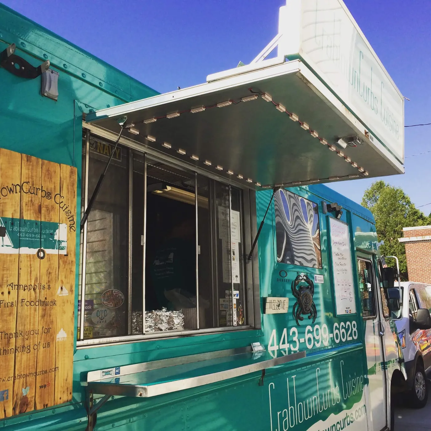 The CrabTown Curbs service window and wooden Annapolis's First Foodtruck sign under a blue sky