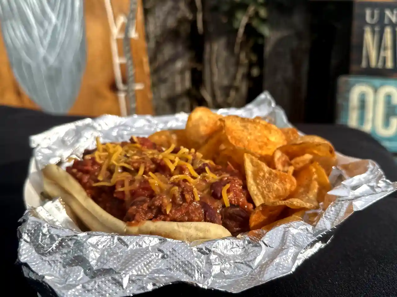 Chili dog topped with cheese, served with chips
