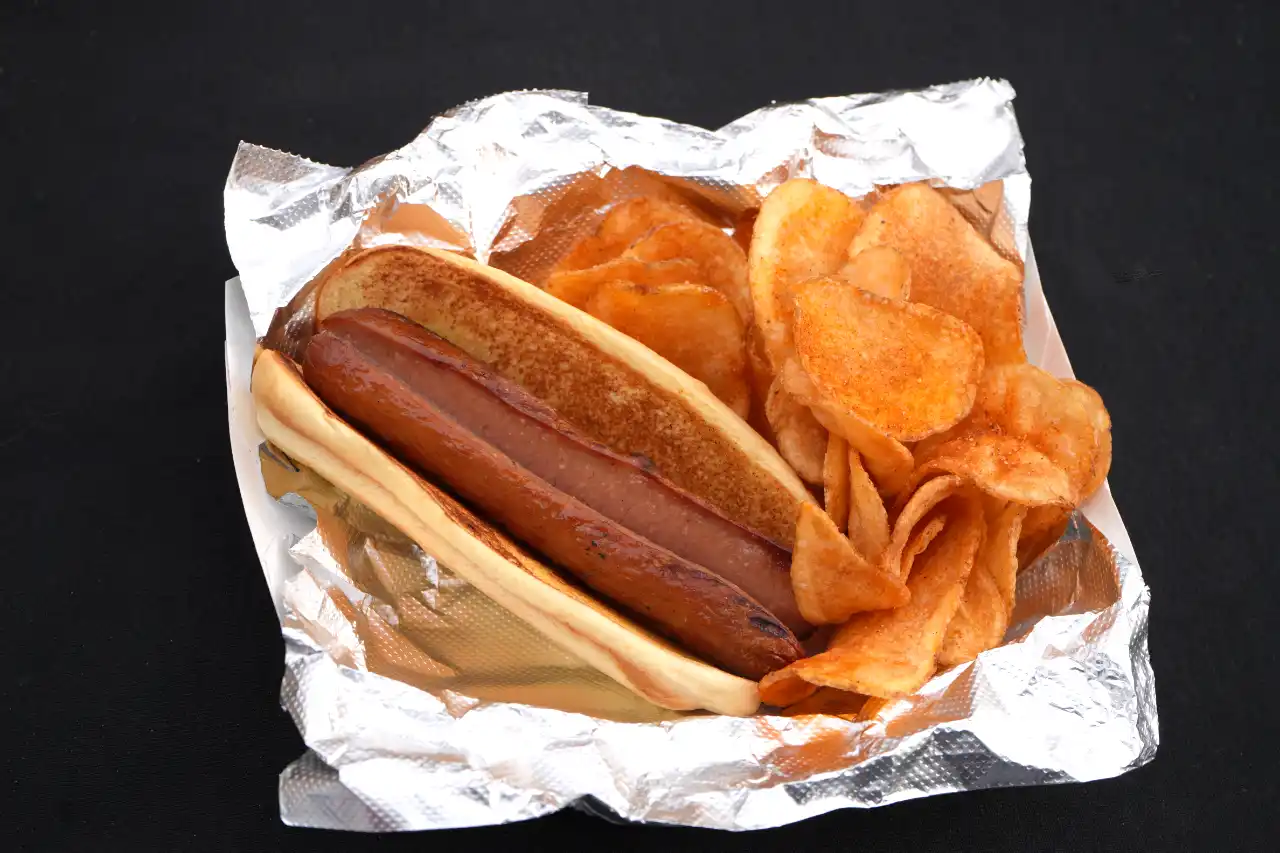 Classic hotdog served with chips in a paper boat